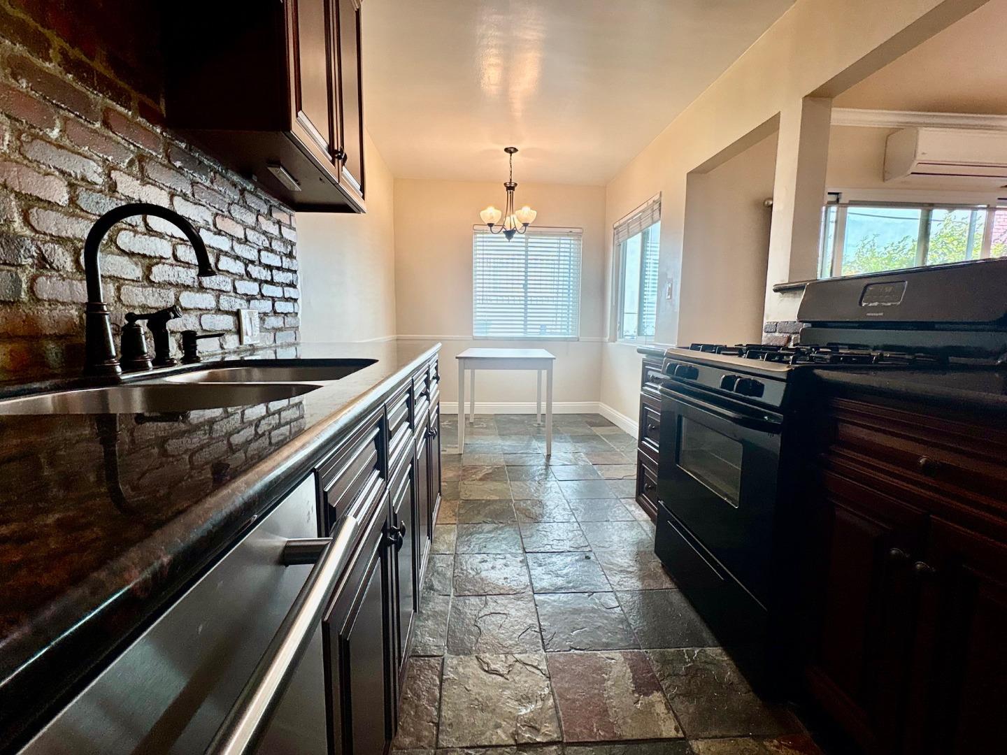 11719 Mayfield Avenue, Unit 1 Los Angeles, CA 90049 - Photo 18 of 28 a kitchen with granite countertop a stove a sink and a microwave