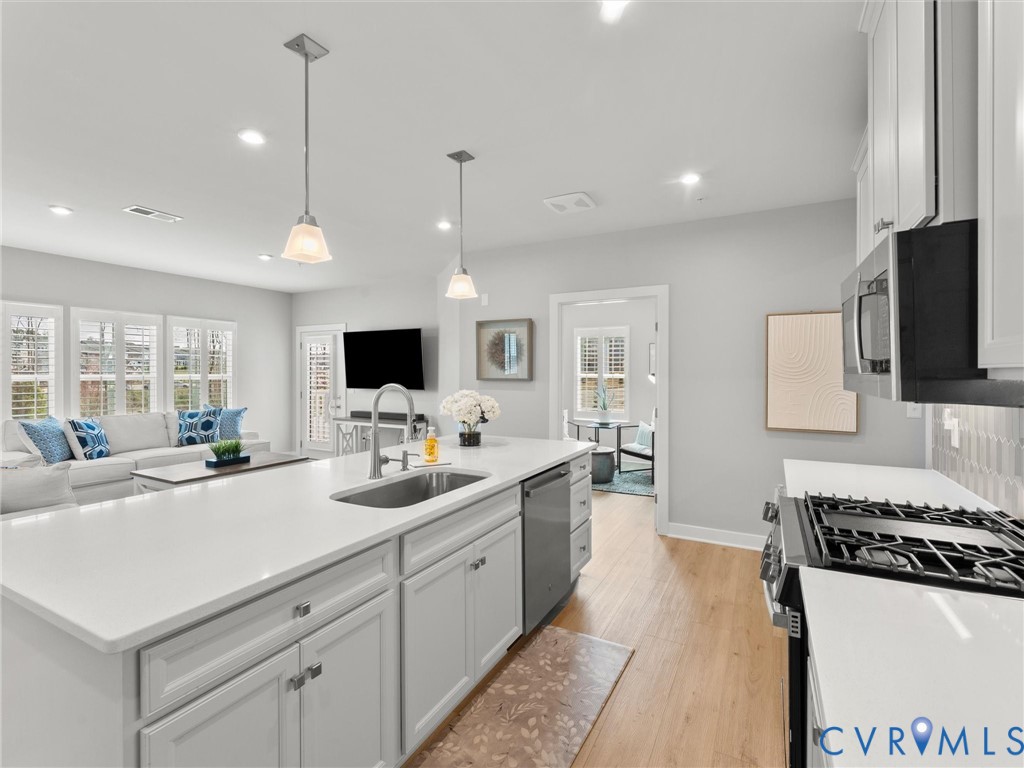 6725 Citory Way, Unit 202 Moseley, VA 23120 - Photo 3 of 42 a large kitchen with kitchen island a sink and a stove top oven with wooden floor