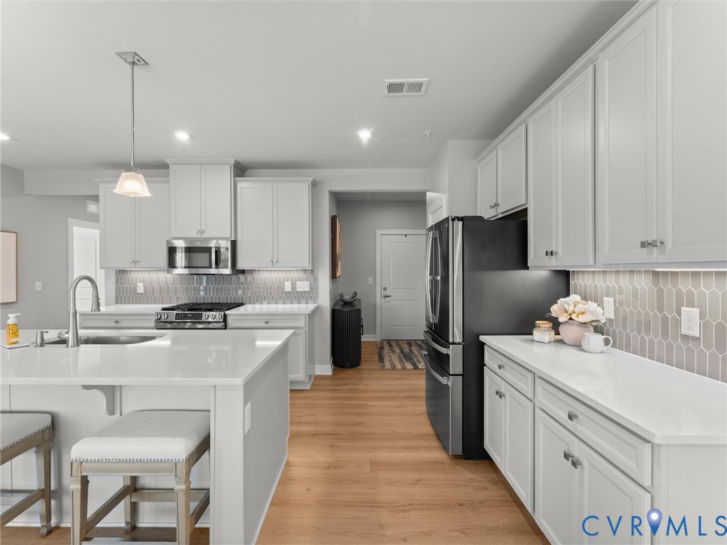 6725 Citory Way, Unit 202 Moseley, VA 23120 - Photo 5 of 42 a kitchen with stainless steel appliances kitchen island granite countertop a refrigerator a sink dishwasher a stove and white cabinets with wooden floor
