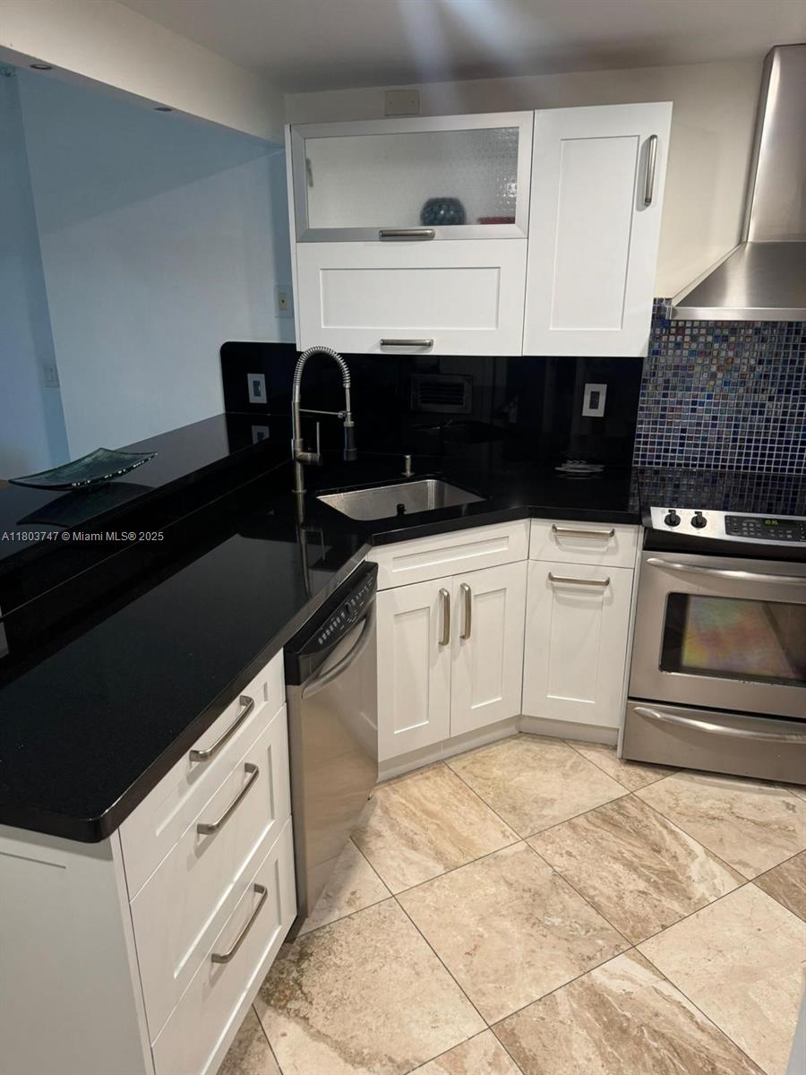 2301 Collins Avenue, Unit 731 Miami Beach, FL 33139 - Photo 16 of 31 a kitchen with granite countertop a stove a sink and white cabinets