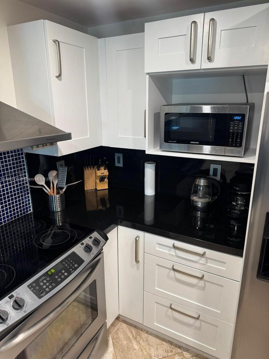 2301 Collins Avenue, Unit 731 Miami Beach, FL 33139 - Photo 6 of 31 a kitchen with a stove and white cabinets