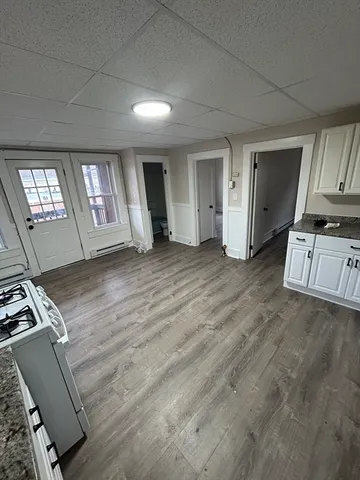 a view of an empty room with window and wooden floor