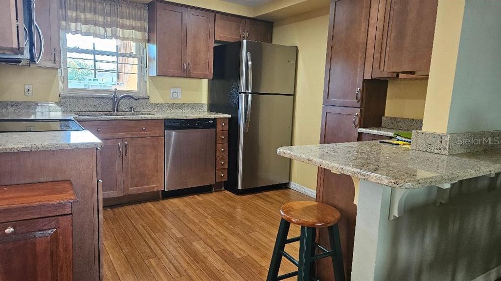 4600 98th Way North, Unit 210 St. Petersburg, FL 33708 - Photo 4 of 33 a kitchen with stainless steel appliances granite countertop a sink refrigerator and microwave
