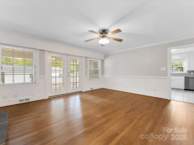a view of an empty room with a window and wooden floor