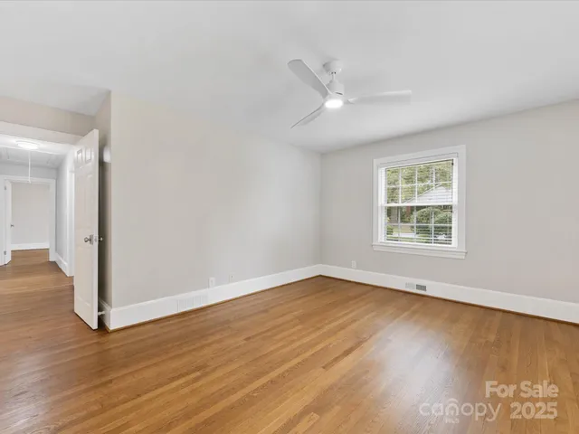 an empty room with wooden floor fan and windows