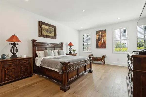 a bedroom with a bed a dresser and next to a window