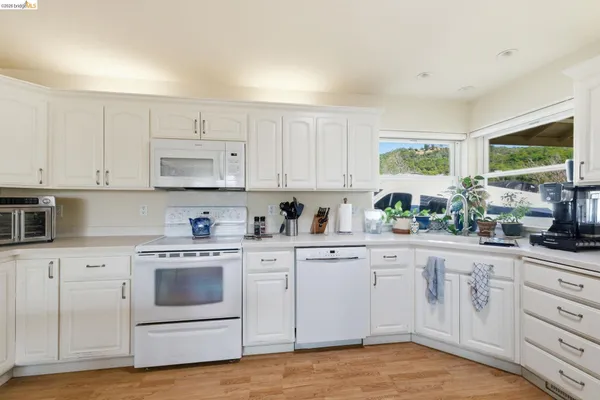 a kitchen with stainless steel appliances granite countertop a refrigerator a stove a sink dishwasher a dining table and chairs with wooden floor