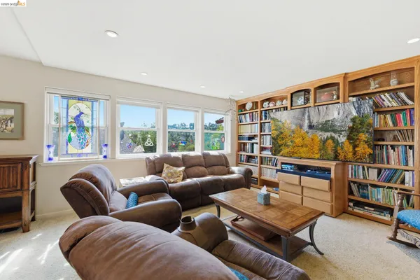 a living room with furniture large windows and wooden floor
