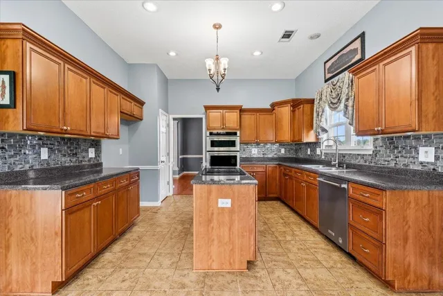 a kitchen with stainless steel appliances granite countertop wooden cabinets a sink dishwasher a stove and a refrigerator