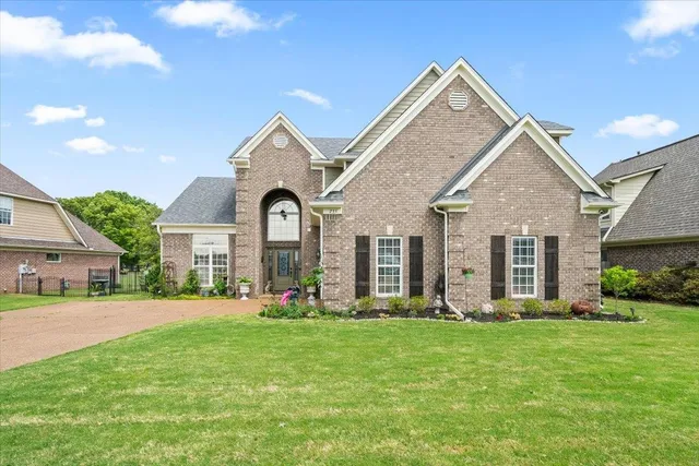 a front view of a house with a yard and trees