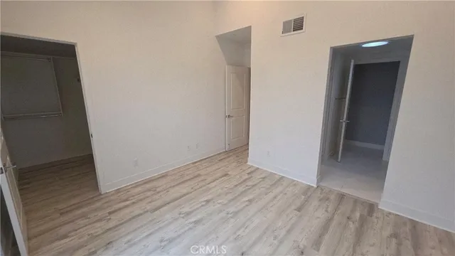 a view of an empty room with wooden floor and closet