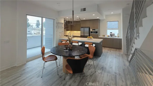 a kitchen with stainless steel appliances a dining table chairs stove refrigerator and cabinets