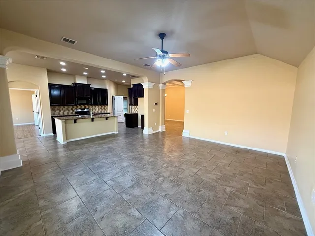 a view of an empty room with window and chandelier fan