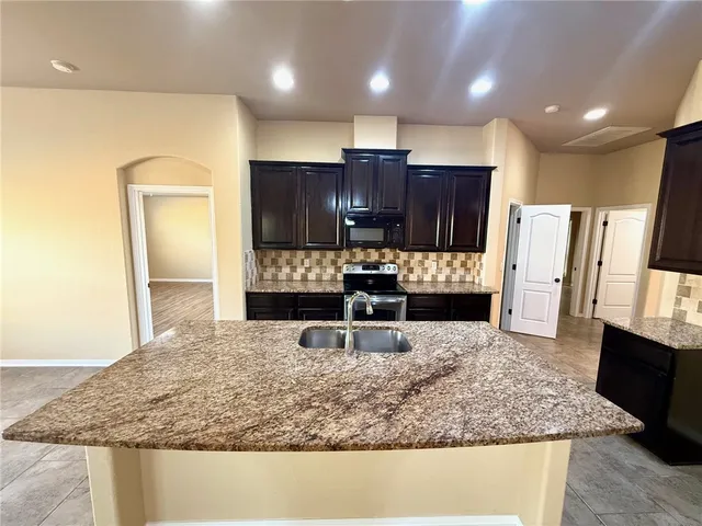 a kitchen with stainless steel appliances granite countertop a sink stove and refrigerator