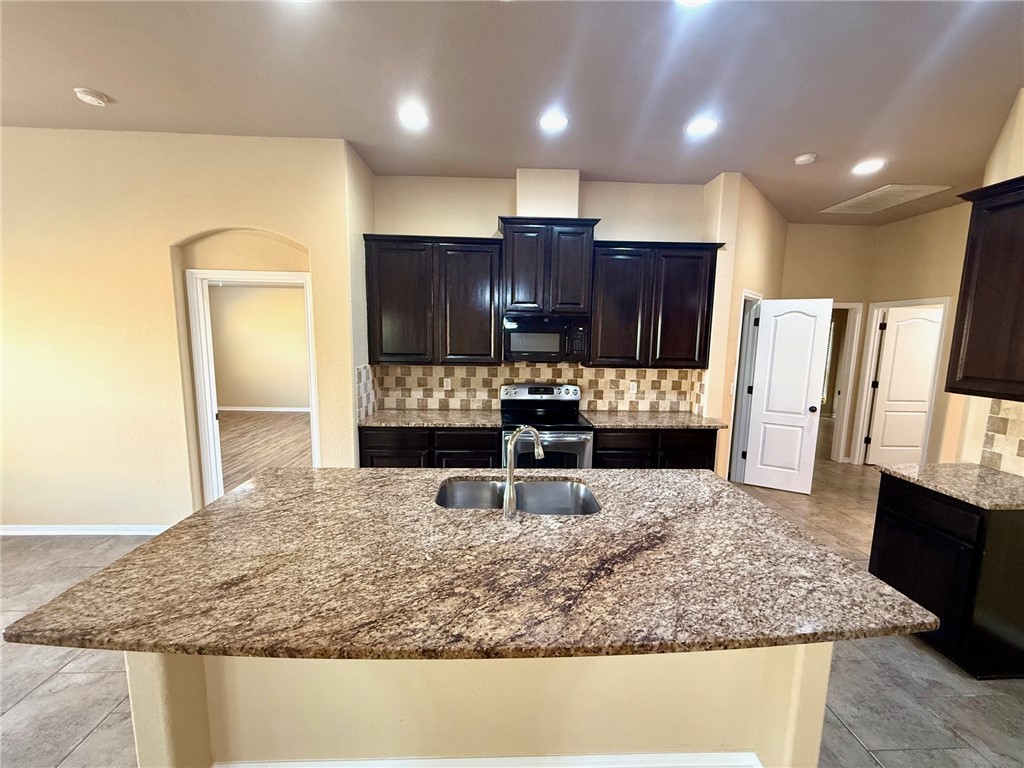 2205 Cardinales Lane Corpus Christi, TX 78414 - Photo 20 of 34 a kitchen with kitchen island granite countertop wooden cabinets a refrigerator and a sink