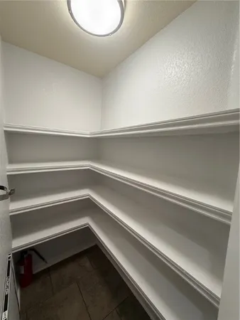 a view of an empty room with wooden floor and a ceiling fan