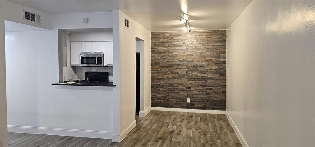 Kitchen with stainless steel microwave, white cabinets, black electric range, dark countertops, and dark wood-style flooring