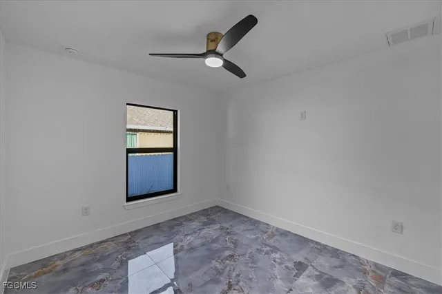 an empty room with windows and ceiling fan