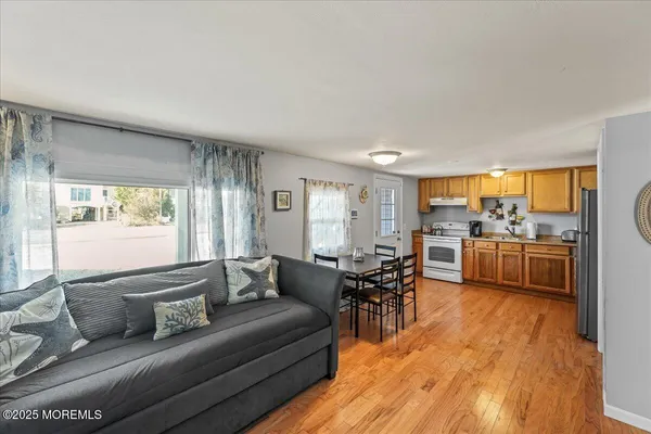 a view of a living room and a kitchen with wooden floor