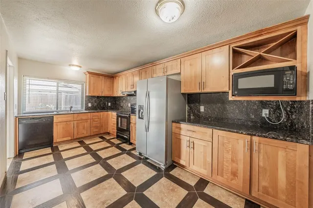 a kitchen with granite countertop a refrigerator stove top oven and sink