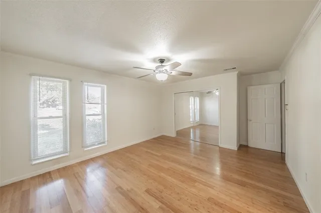 a view of empty room with wooden floor and fan