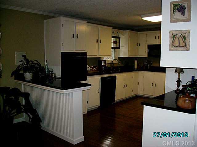 7680 Stokes Ferry Road Salisbury, NC 28146 - Photo 5 of 16 a kitchen with granite countertop a refrigerator a stove and wooden floor