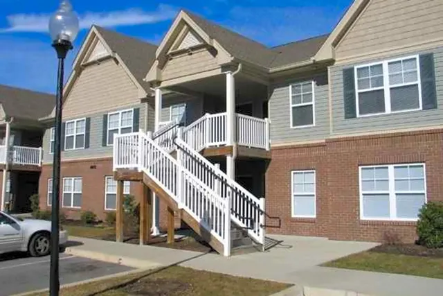 a view of a brick house with many windows next to a road