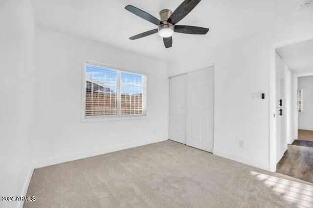 an empty room with ceiling fan and windows