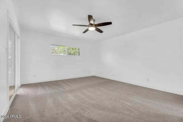 an empty room with a ceiling fan and window