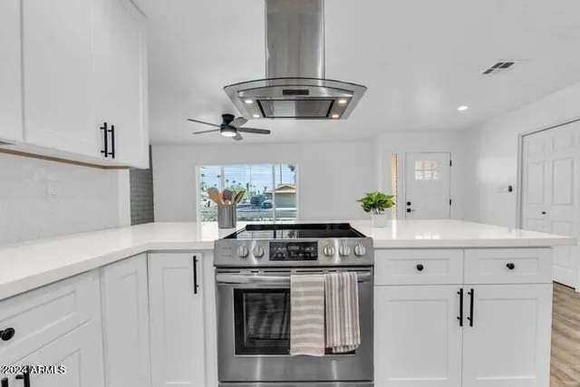 a kitchen with stainless steel appliances a stove and white cabinets