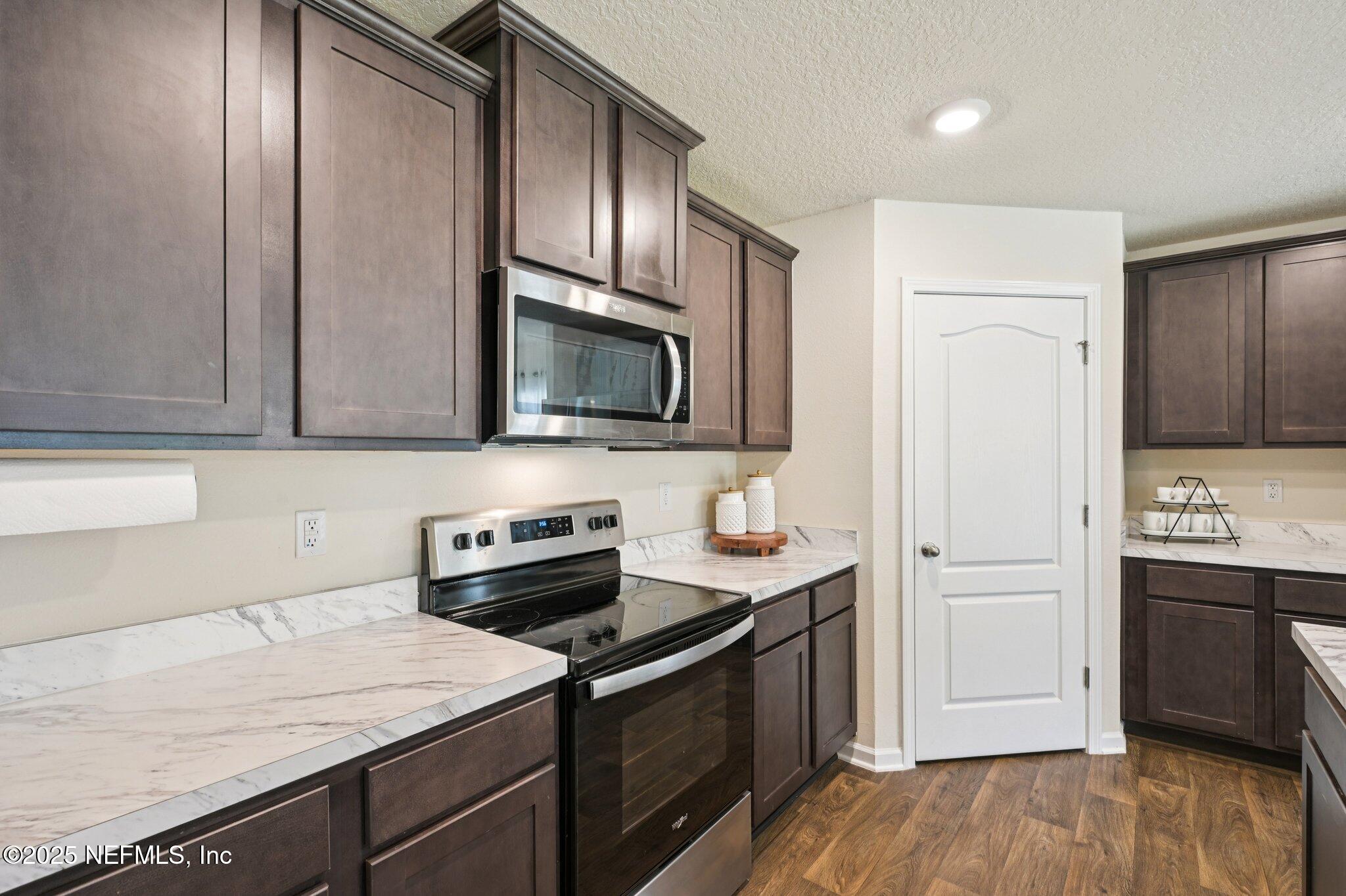 1143 Morgans Treasure Road St. Augustine, FL 32084 - Photo 13 of 39 a kitchen with stainless steel appliances a sink dishwasher a stove and a refrigerator with wooden floor