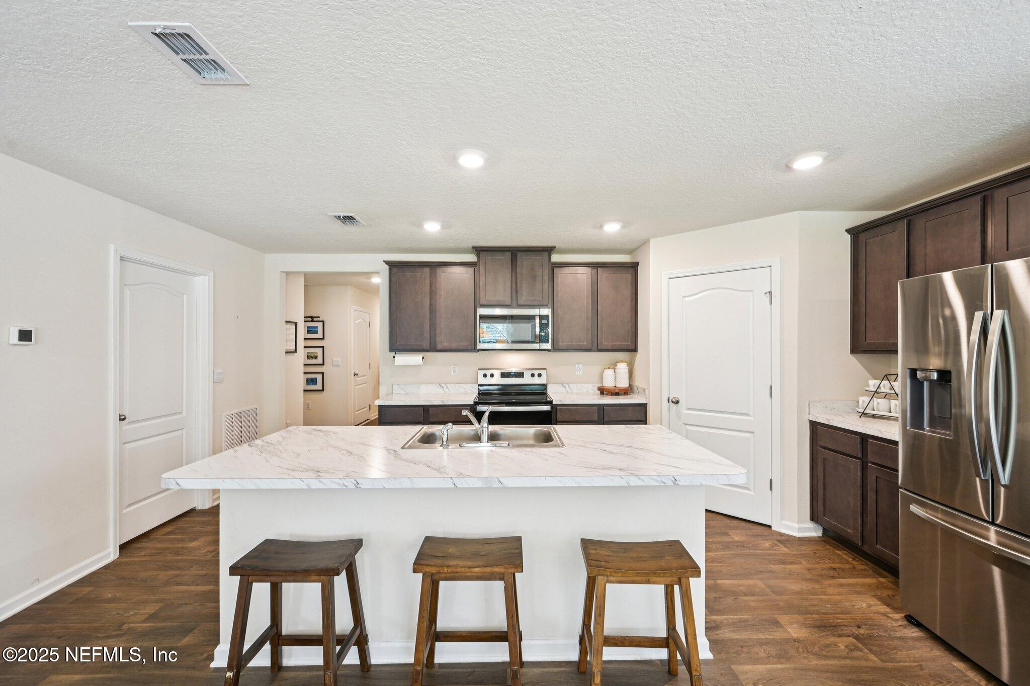 1143 Morgans Treasure Road St. Augustine, FL 32084 - Photo 16 of 39 a kitchen with stainless steel appliances granite countertop a kitchen island hardwood floor and a refrigerator