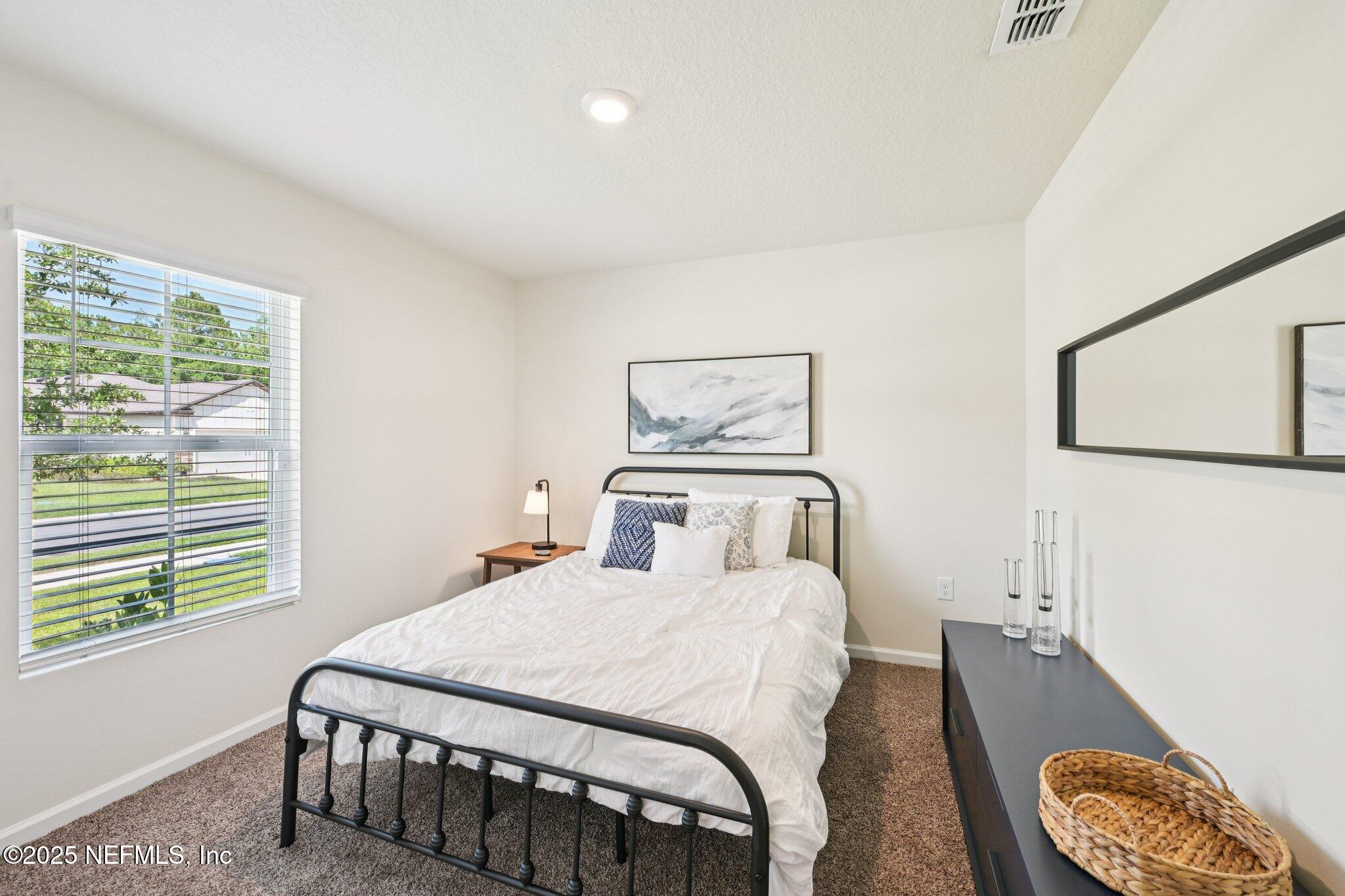 1143 Morgans Treasure Road St. Augustine, FL 32084 - Photo 21 of 39 a bedroom with a bed a couch and a window