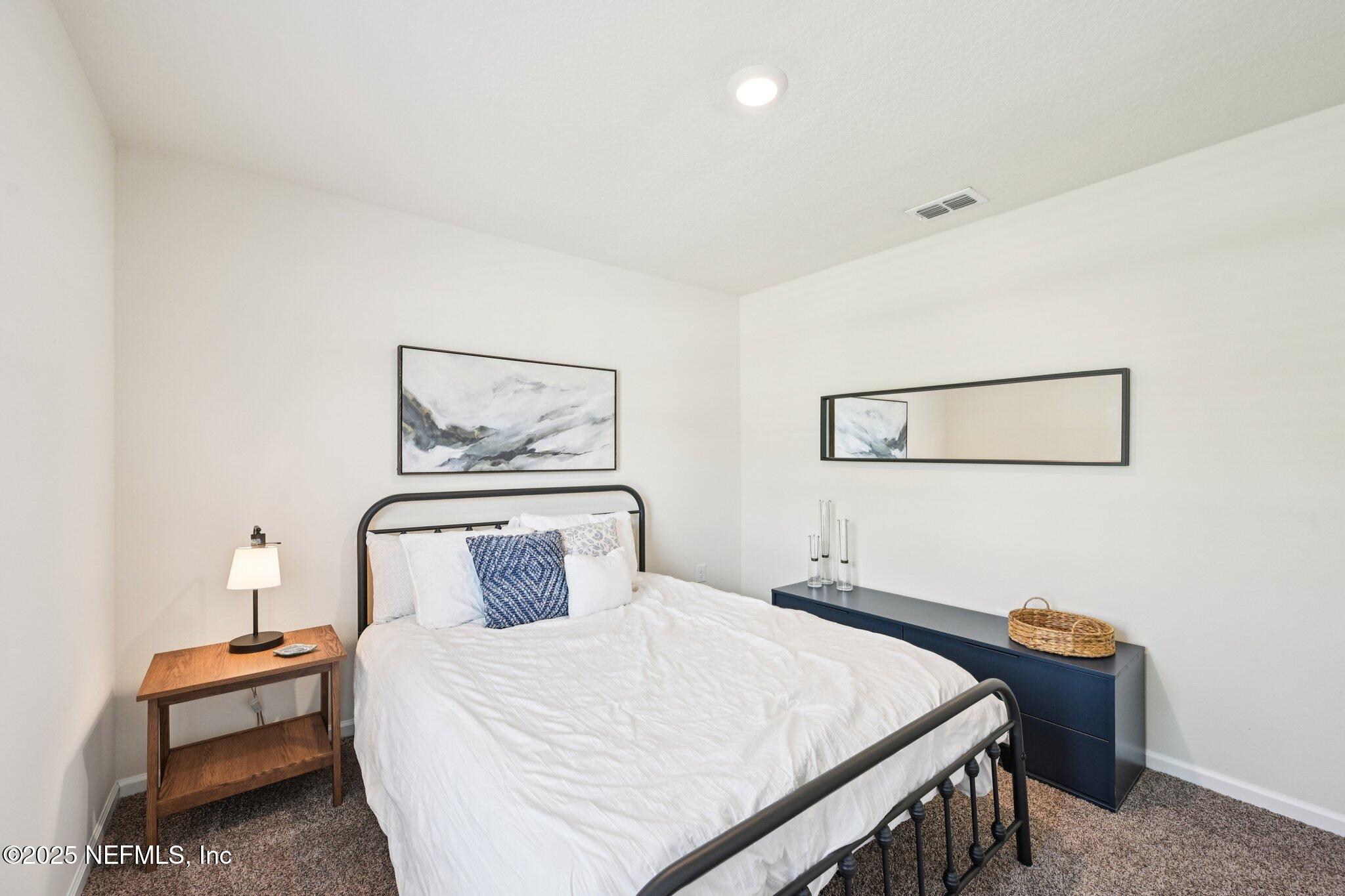 1143 Morgans Treasure Road St. Augustine, FL 32084 - Photo 22 of 39 a bedroom with a bed and a lamp