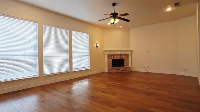 an empty room with wooden floor fireplace and window