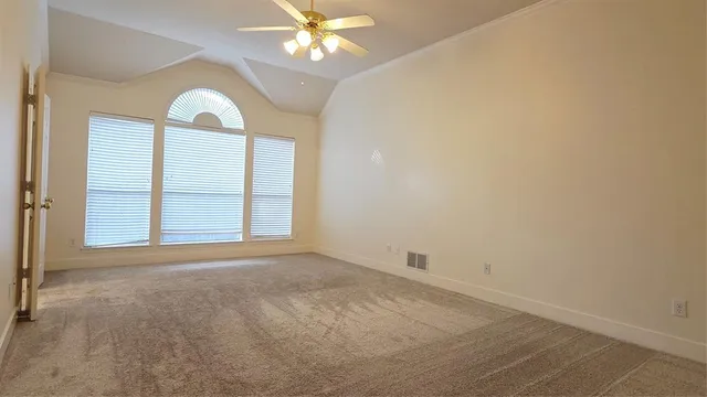 an empty room with windows and chandelier fan