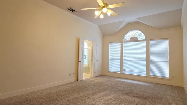 an empty room with a chandelier fan and windows