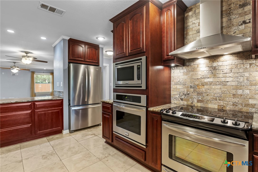 3745-3735 Canyon Heights Road Belton, TX 76513 - Photo 17 of 45 a kitchen with granite countertop wooden cabinets and stainless steel appliances