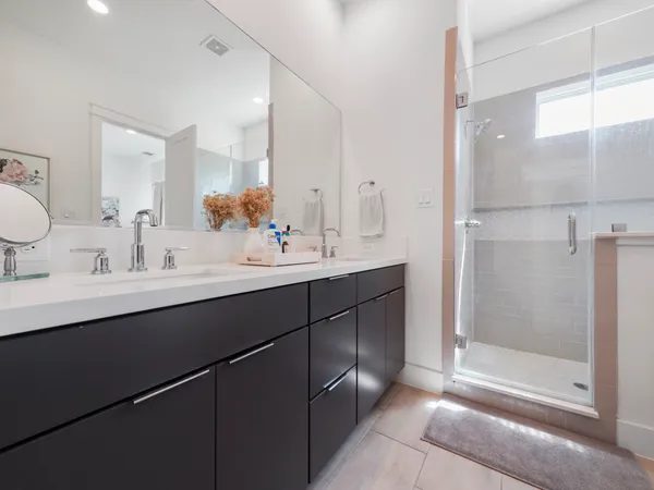 a bathroom with a double vanity sink mirror and shower