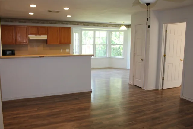 a kitchen with stainless steel appliances granite countertop a refrigerator a sink dishwasher a stove and a microwave oven on the wooden floor