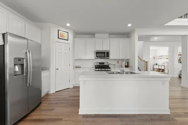 a view of a kitchen with kitchen island a sink wooden floor and refrigerator