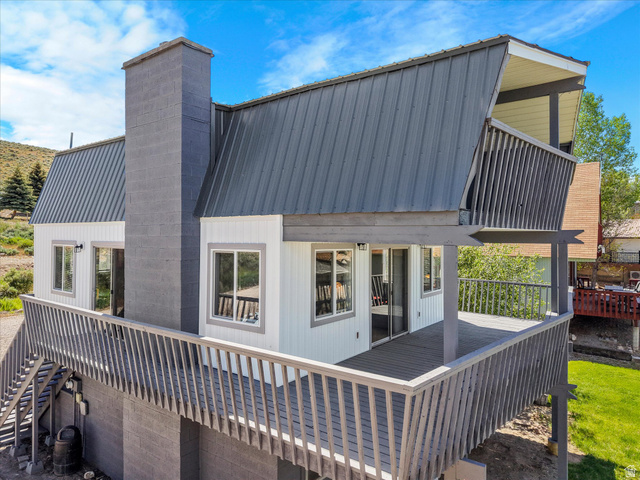85 B Street, Unit 22 St. Charles, ID 83272 - Photo 30 of 35 Two story residence featuring a large wrap-around deck, multiple sliding glass doors, a prominent chimney, and a durable metal roof