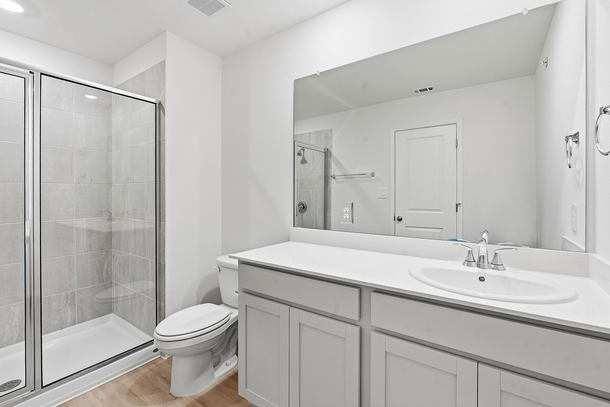 164 Cinnabar Lane, Unit 3 Kyle, TX 78640 - Photo 14 of 20 Bathroom featuring a glass-enclosed shower with tile surround, a single vanity with an undermount sink, light-toned cabinetry, a white countertop, and wood-finish flooring
