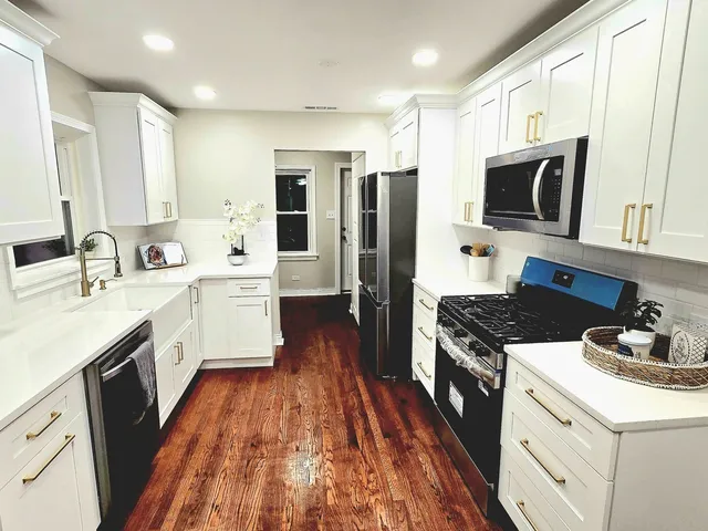 a large kitchen with stainless steel appliances a stove a sink dishwasher a refrigerator and a microwave oven with wooden floor