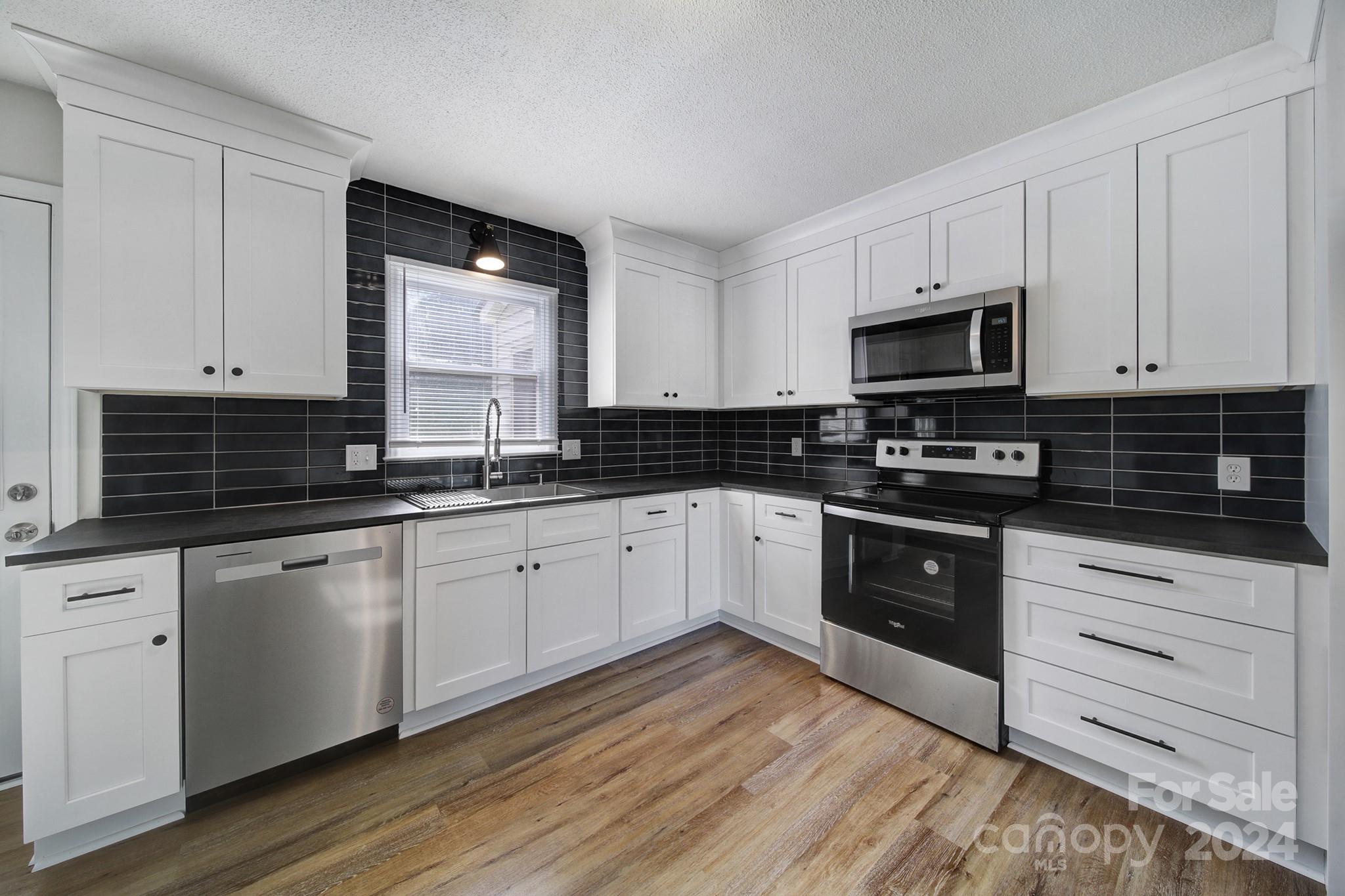 a kitchen with granite countertop wooden cabinets and black stainless steel appliances