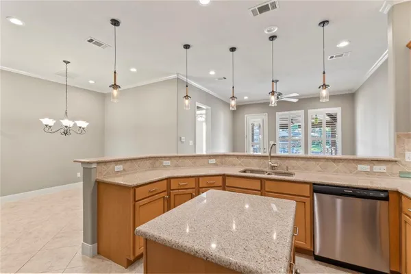 an empty room with kitchen view and a ceiling fan