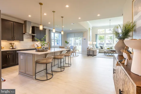 a kitchen with stainless steel appliances kitchen island granite countertop a refrigerator a stove a sink a dining table and chairs with wooden floor