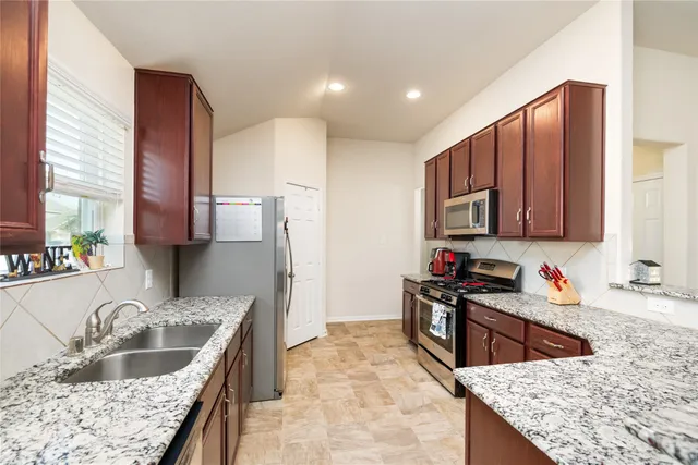 a kitchen with stainless steel appliances granite countertop a sink stove and refrigerator