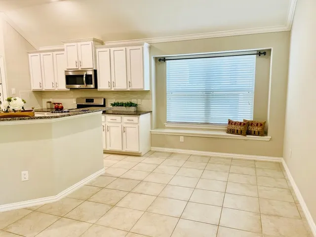 a kitchen with stainless steel appliances a stove a sink and white cabinets