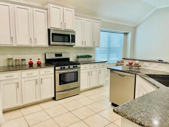 a kitchen with granite countertop cabinets stainless steel appliances and a sink